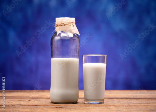 Milk in a glass bottle. Milk poured into a glass. Fresh milk in a bottle and a glass standing on a wooden table.