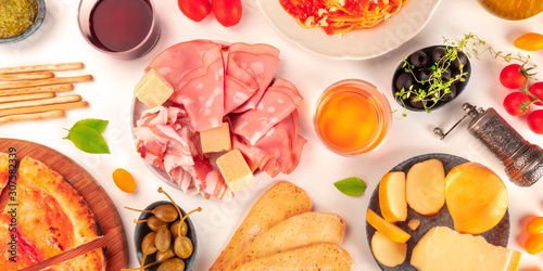 Italian food panorama. Pizza, cheese, ham, wine, olives, capers, shot from above on a white background