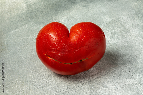 Ugly Organic Vegetable - Single red heart-shaped tomato on a gray background