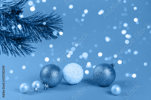 Christmas background  spruce branch  a group of beautiful toys  Christmas balls  on a blue festive background with lights of lanterns and falling snow.