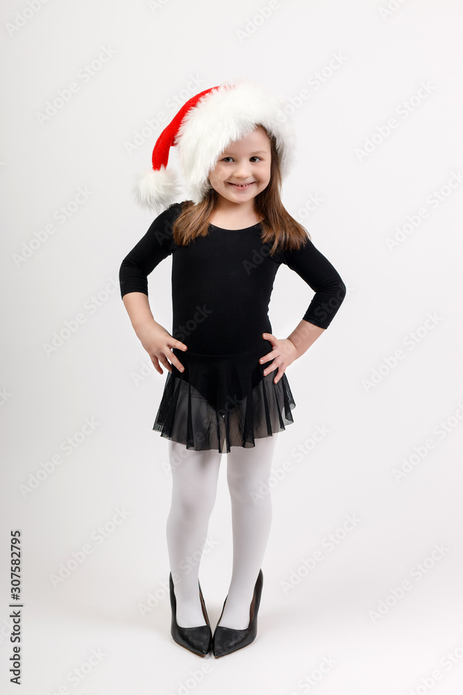 Little girl in ballerina costume and santa claus hat is standing and smiling. Little girl in ballerina costume and santa claus hat is standing and smiling.