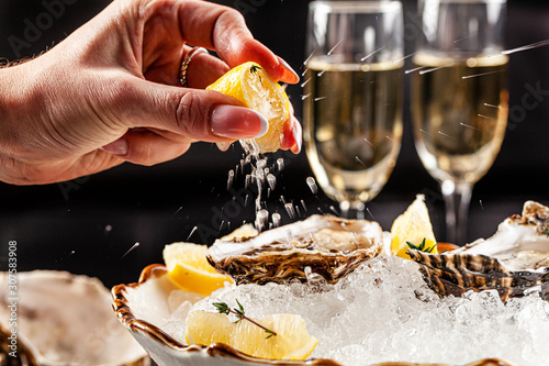 Prosecco bar concept. Open oysters lie on crushed ice with lemon and lime, next to a glass of champagne. Background image. Copy space. photo