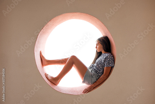 Young barefoot girl curled inside a round opening photo