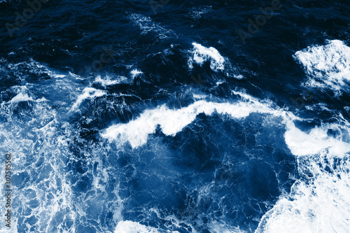 Top view on blue ocean waves and foam.