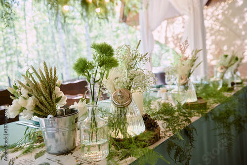 Beautiful floral arrangement in glass vase on wedding table in restaurant, copy space. Luxury wedding decorations. Table setting