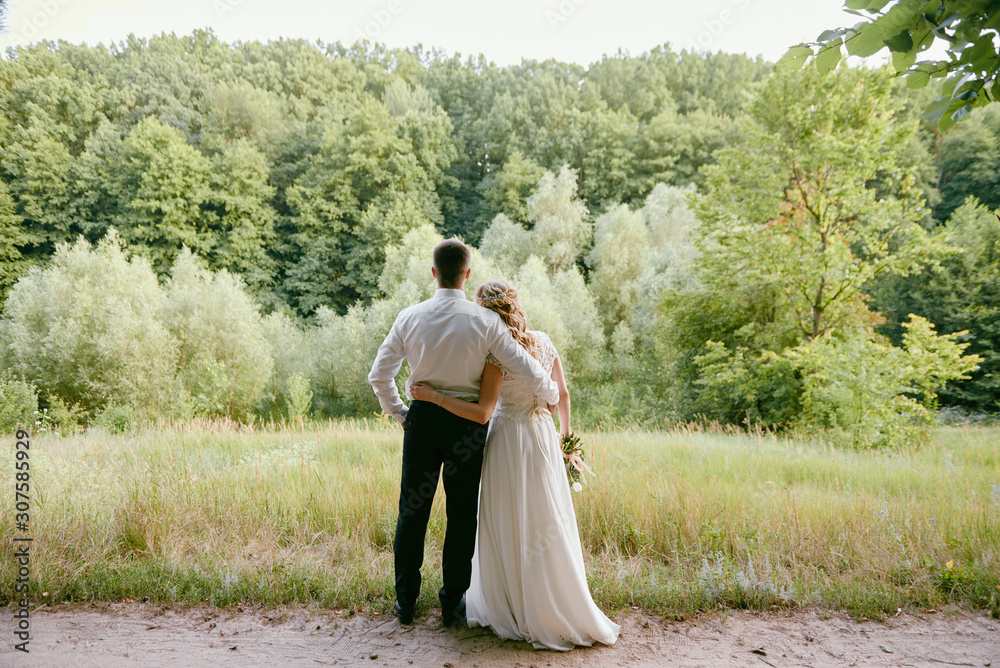 Full length body portrait of young bride and groom walking on park ...