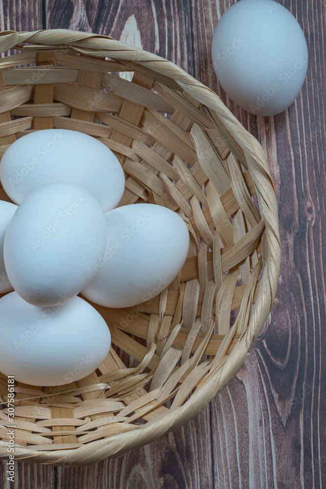 several fresh chicken eggs in a straw basket on a wooden background. Healthy eating concept several fresh chicken eggs in a straw basket on a wooden background. Healthy eating concept