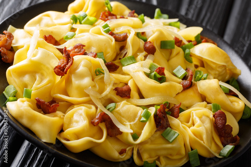 Italian traditional tortelloni with bacon, cheese and green onions close-up in a plate on the table. horizontal photo