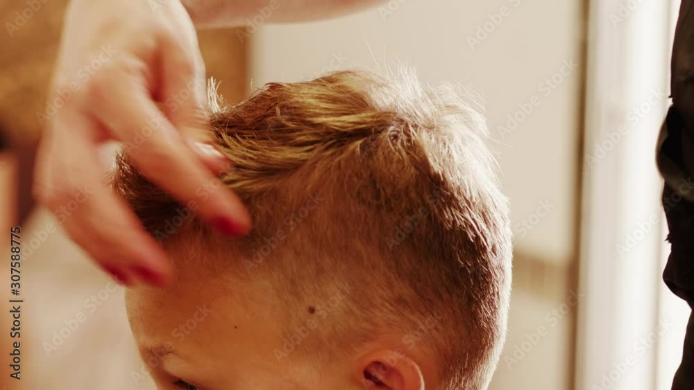 Barber hands styling boy blond hair after cutting for man head-dress in hairdressing beauty saloon. Hairdresser setting teenager hair on head making style haircut by fingers in barbershop. Fixing hair Barber hands styling boy blond hair after cutting for man head-dress in hairdressing beauty saloon. Hairdresser setting teenager hair on head making style haircut by fingers in barbershop. Fixing hair