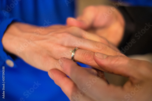 close-up of male putting wedding ring on finger of his wife.