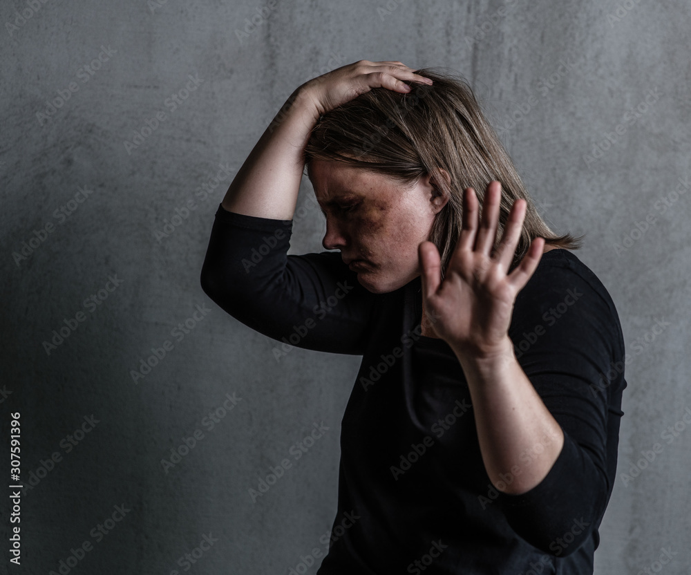 Crying woman victim of domestic violence and abuse showing a stop sign and closes her head with her hand Crying woman victim of domestic violence and abuse showing a stop sign and closes her head with her hand