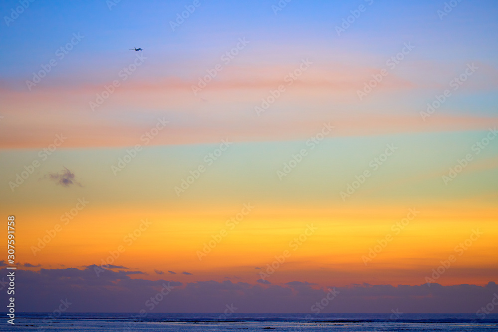 Plane flying in front of colorful tropical sunset in famous tour