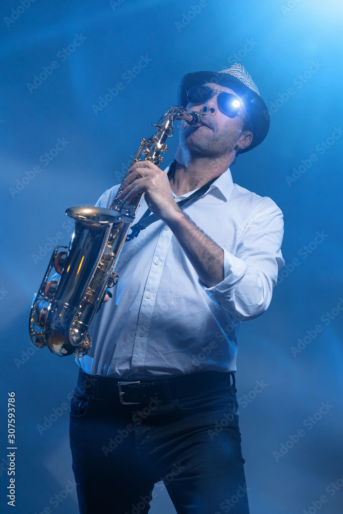 Fototapeta premium Man playing sax in cold blue laserlight