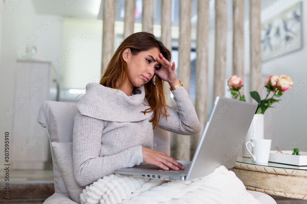 Beautiful tired business woman is holding her head massaging her nose bridge while working on the laptop. Beautiful tired business woman is holding her head massaging her nose bridge while working on the laptop.