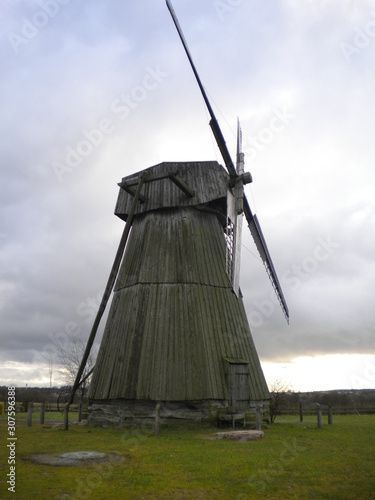 Summer landscape with old windmill on the ground against dark sky with clouds and clouds.