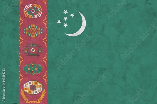 Turkmenistan flag depicted in bright paint colors on old relief plastering wall. Textured banner on rough background photo