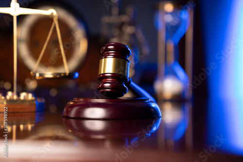 Law concept. Judge’s gavel, scale and old clock on dark background.