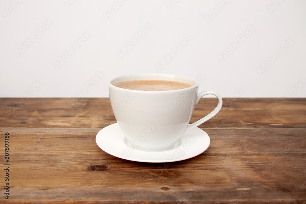 Cappuccino coffee in a white cup and saucer on an old wooden table, concept of a stylish cafe Cappuccino coffee in a white cup and saucer on an old wooden table, concept of a stylish cafe