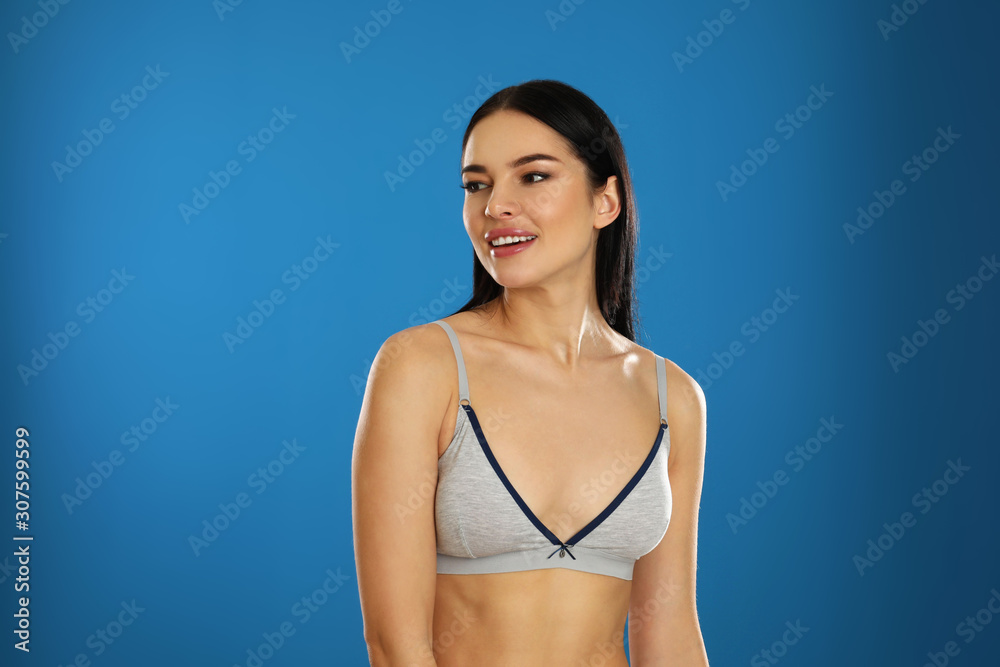 Naklejka premium Beautiful young woman in grey sportive underwear on blue background