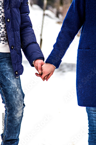 Loving couple in sweaters hugging, holding hands in the winter in nature