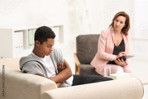 Psychotherapist working with teenage African-American boy in office