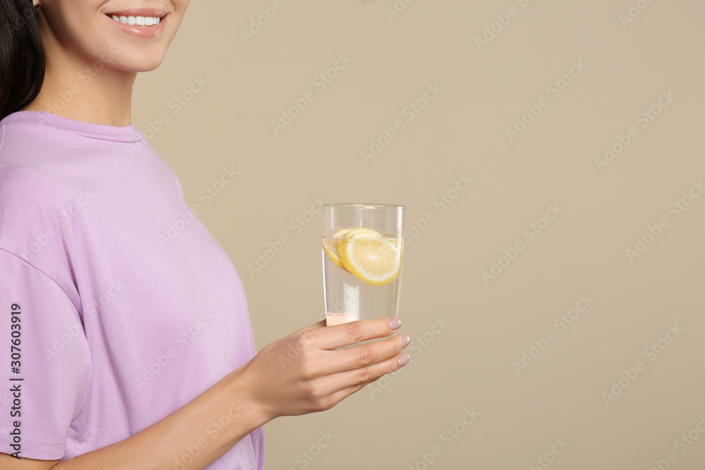 Woman with tasty lemon water on beige background, closeup. Space for text Woman with tasty lemon water on beige background, closeup. Space for text