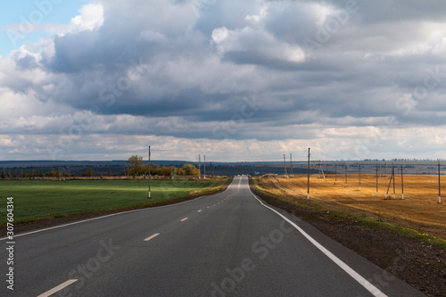 road landscape with dramatic clouds, green and yellow fields, space for text