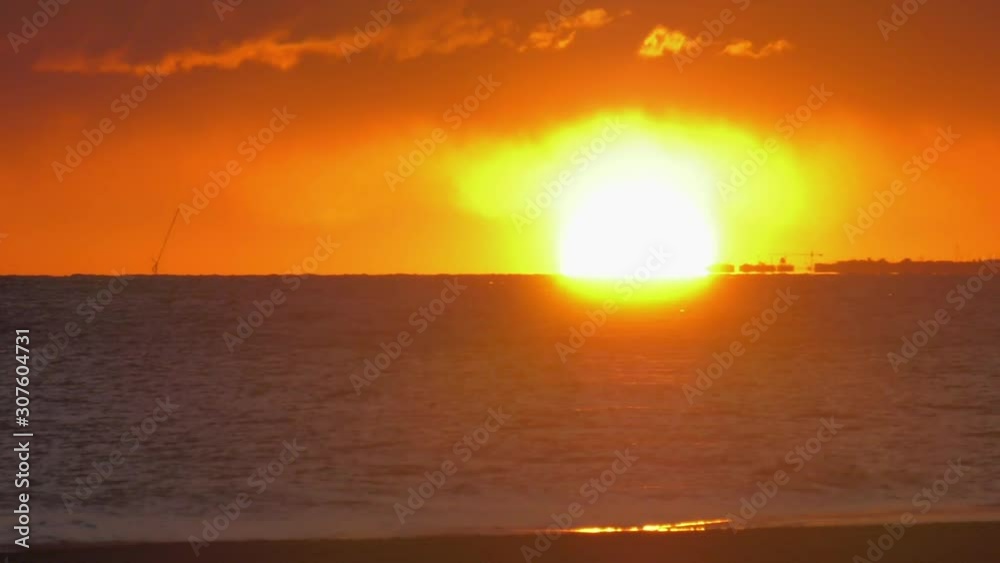 Hazy beach sunrise in orange sky over dark ocean waves, coastal seascape Spain Hazy beach sunrise in orange sky over dark ocean waves, coastal seascape Spain