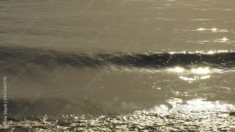 Gentle ocean waves at dawn on rippled water reflecting sunlight, slow motion abstract Gentle ocean waves at dawn on rippled water reflecting sunlight, slow motion abstract