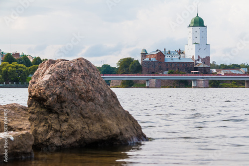 A boulder on the coast of Gulf of Finland on the background of the Vyborg Castle on overcast day, Vyborg, Leningrad Oblast, Russia photo