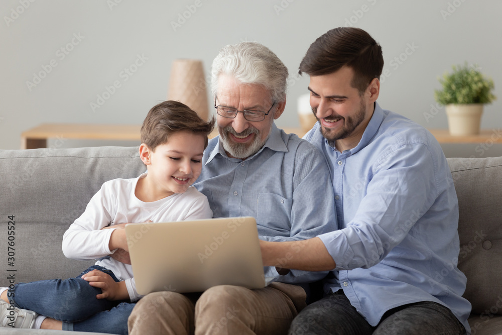 Happy multi generational men having fun using laptop at home Happy multi generational men having fun using laptop at home