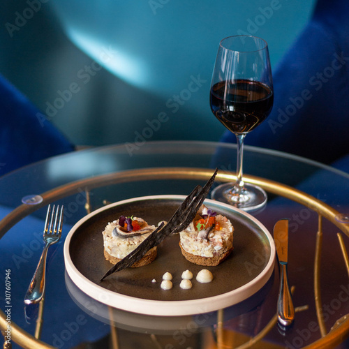 Glass of red wine with fish starter and brawn bread on a glass table