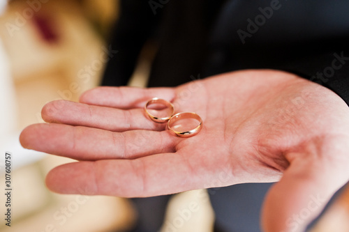 Morning of the groom preparation. Young and handsome groom hold wedding rings on hand.