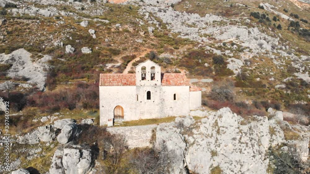 Rustic old church isolated among rocks and ruins, bright orange tiles, slow aerial pan footage Rustic old church isolated among rocks and ruins, bright orange tiles, slow aerial pan footage