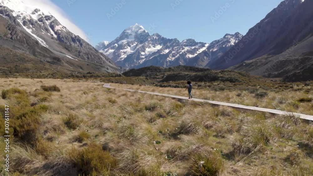 girl hinking towards mount cook new zealand fully visbible dolly in 4k grassland