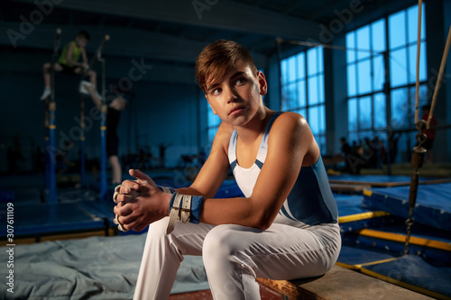 Little male gymnast training in gym  flexible and active. Caucasian fit little boy  athlete in white sportswear preparing for exercises for strength  balance. Movement  action  motion  dynamic concept