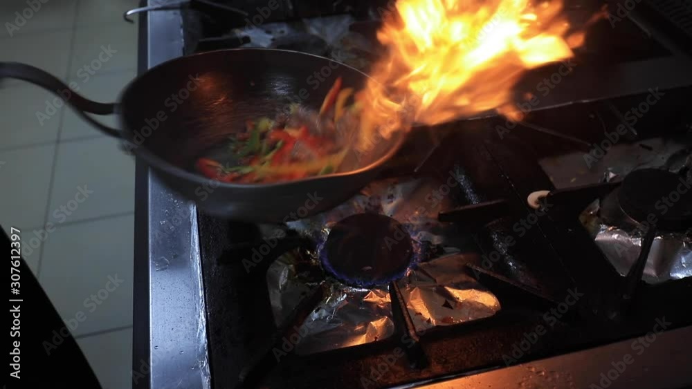 Chef holding frying pan in hand and mixes vegatable and meat Chef holding frying pan in hand and mixes vegatable and meat