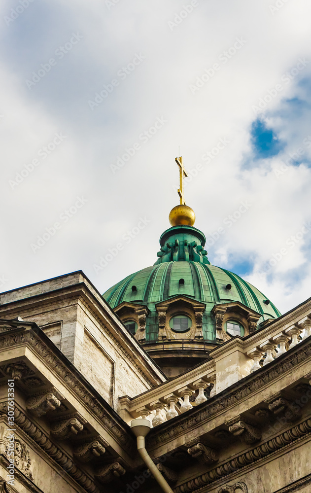 Close-up of the dome of the Kazan Cathedral with a golden cross part of a wall with columns and a frieze with windows, porticoes on a clear day.  St Petersburg, Russia