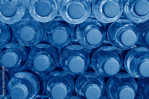 Fotografie Rows of many transparent plastic bottles with drinking water supply in white refrigerator