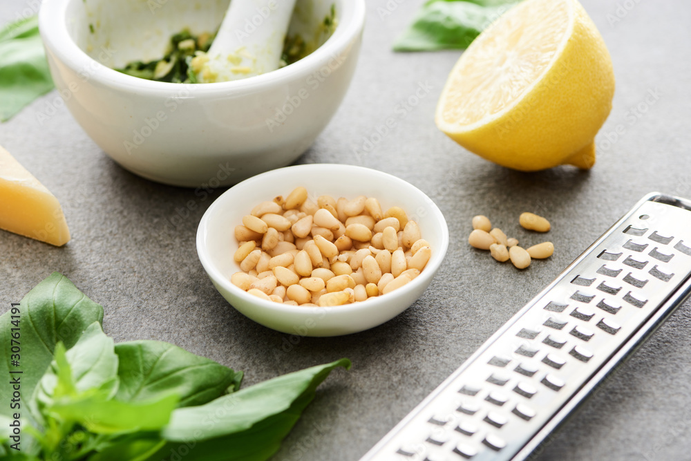 close up view of pesto sauce raw ingredients and cooking utensils on grey surface close up view of pesto sauce raw ingredients and cooking utensils on grey surface