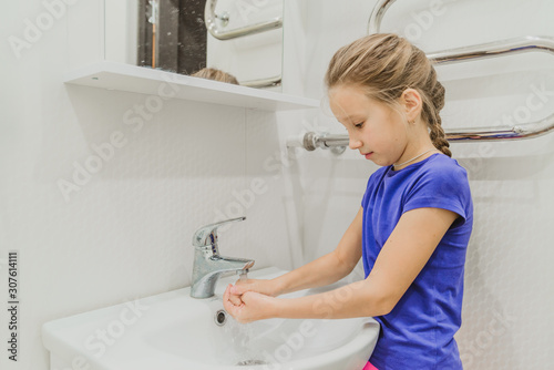 The child washes his hands in the bathroom.  wash hands with soap close-up. concept of hygiene and cleanliness. tap water