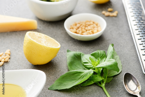 close up view of pesto sauce raw ingredients and cooking utensils on grey surface