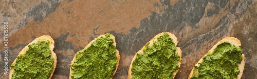 flat lay with baguette slices with delicious pesto sauce on stone surface, panoramic shot