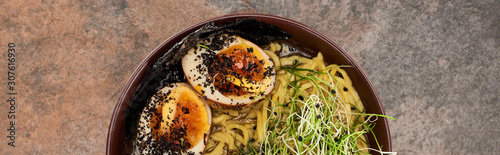 top view of spicy ramen with egg on stone surface, panoramic shot