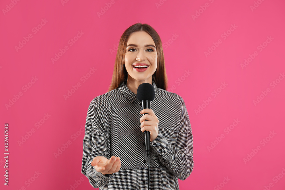 Young female journalist with microphone on pink background Young female journalist with microphone on pink background