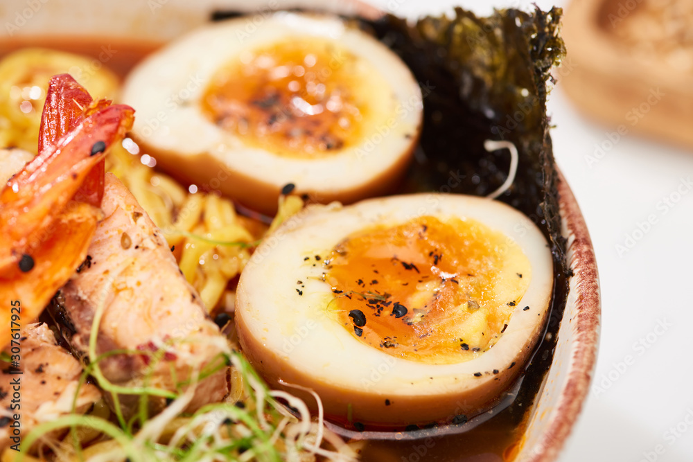 close up view of spicy seafood ramen with egg in bowl