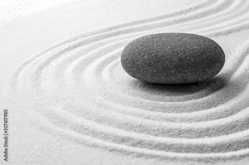 Grey stone on sand with pattern. Zen, meditation, harmony