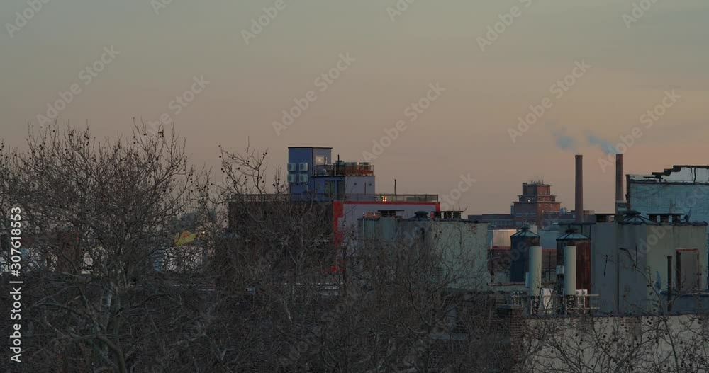 Brooklyn skyline after sunset with smoke coming out of two tall smoke stacks and bare winter trees in foreground 4K CINEMATIC Brooklyn skyline after sunset with smoke coming out of two tall smoke stacks and bare winter trees in foreground 4K CINEMATIC