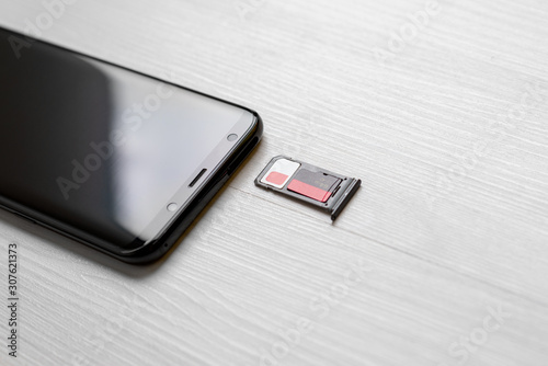 SIM card and memory card in adapter beside smart phone on desk close-up