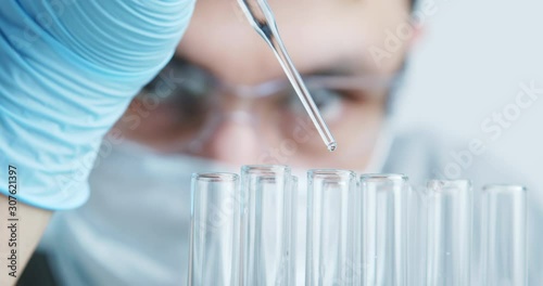 Technician carefully drips the solution from the pipette into glass tubes for DNA analysis.